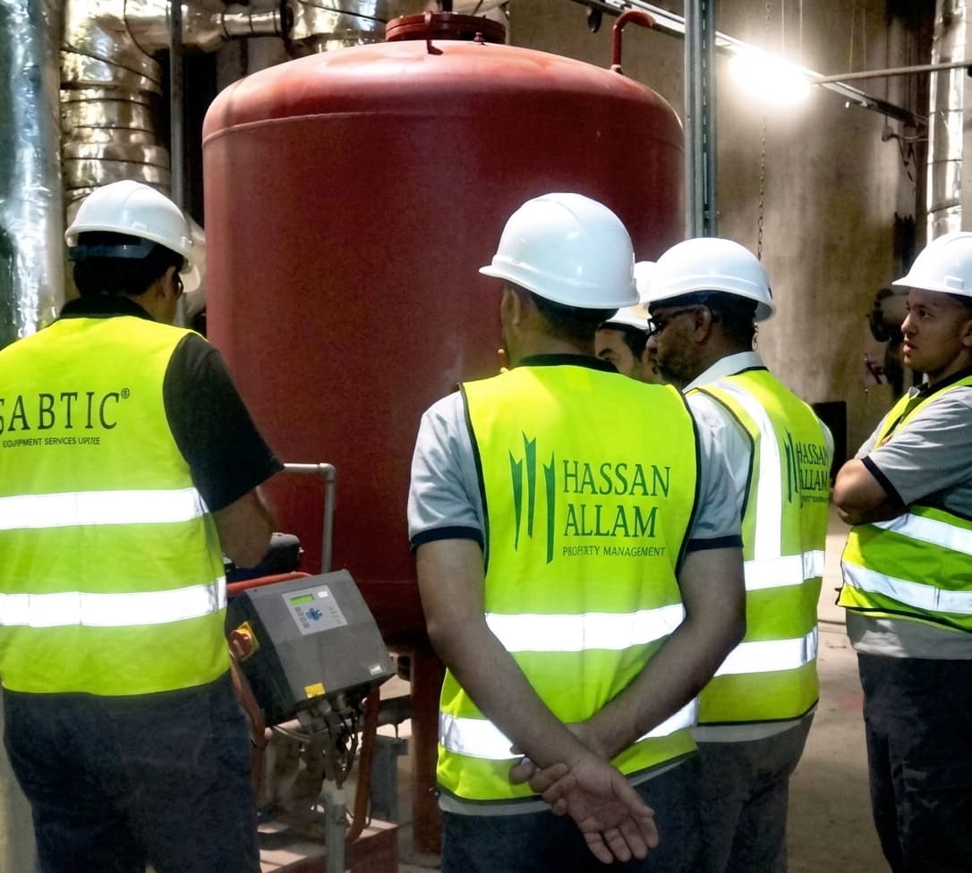 Gabtic engineer briefing Hassan Allam property management staff beside an expansion tank in a plant room
